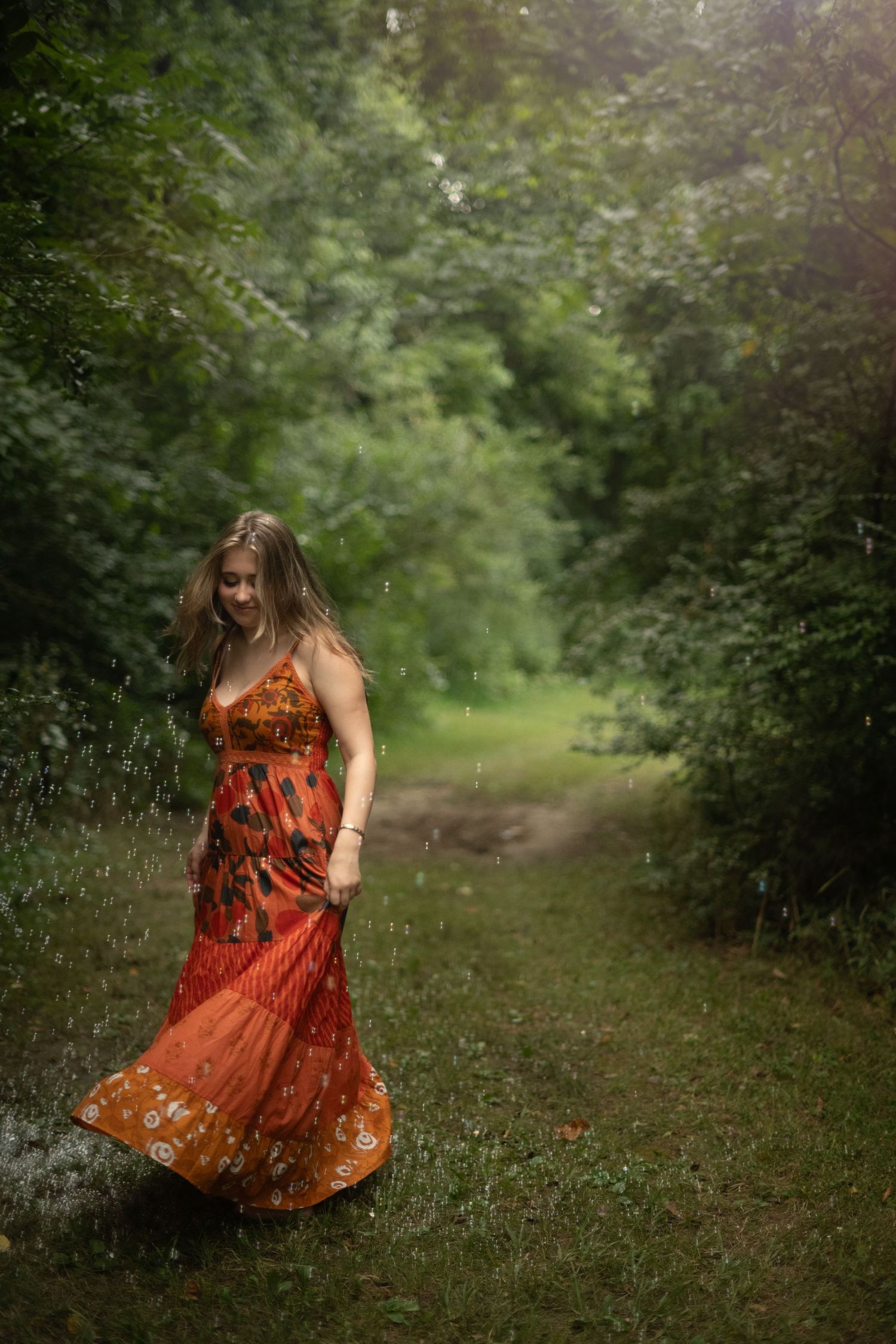 A person in a light blue floral dress stands gracefully among blooming white wildflowers in a sunny meadow.