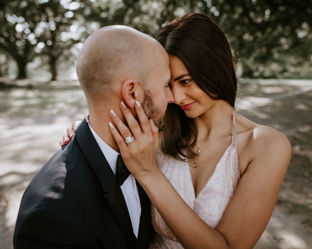 Close-up of bride and groom touching foreheads, showcasing elegant diamond engagement ring.