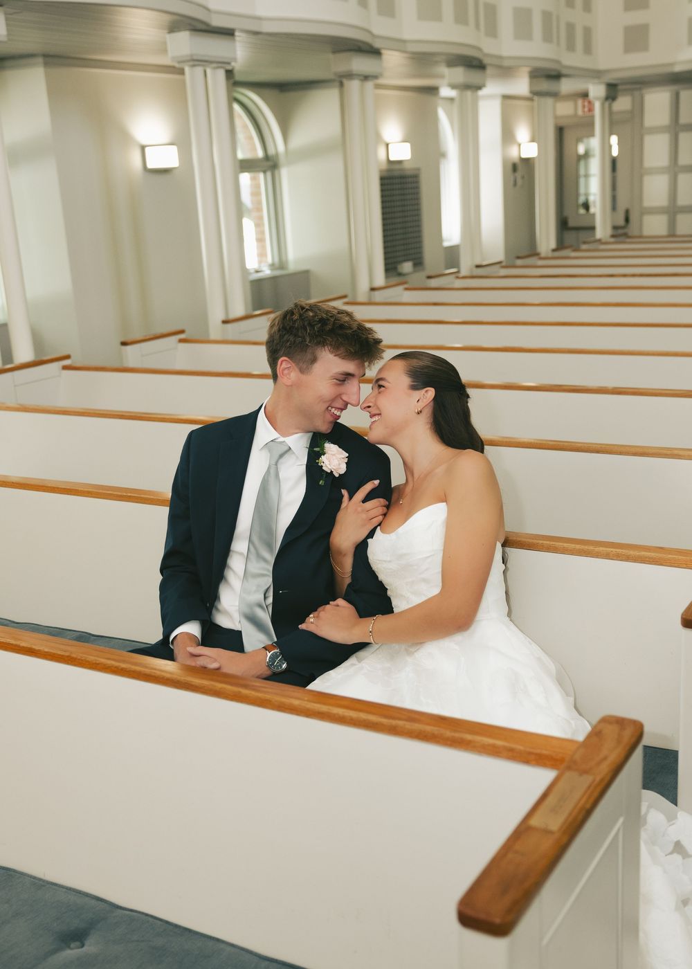Bride and groom sitting together in church pews, sharing an intimate moment on their wedding day.