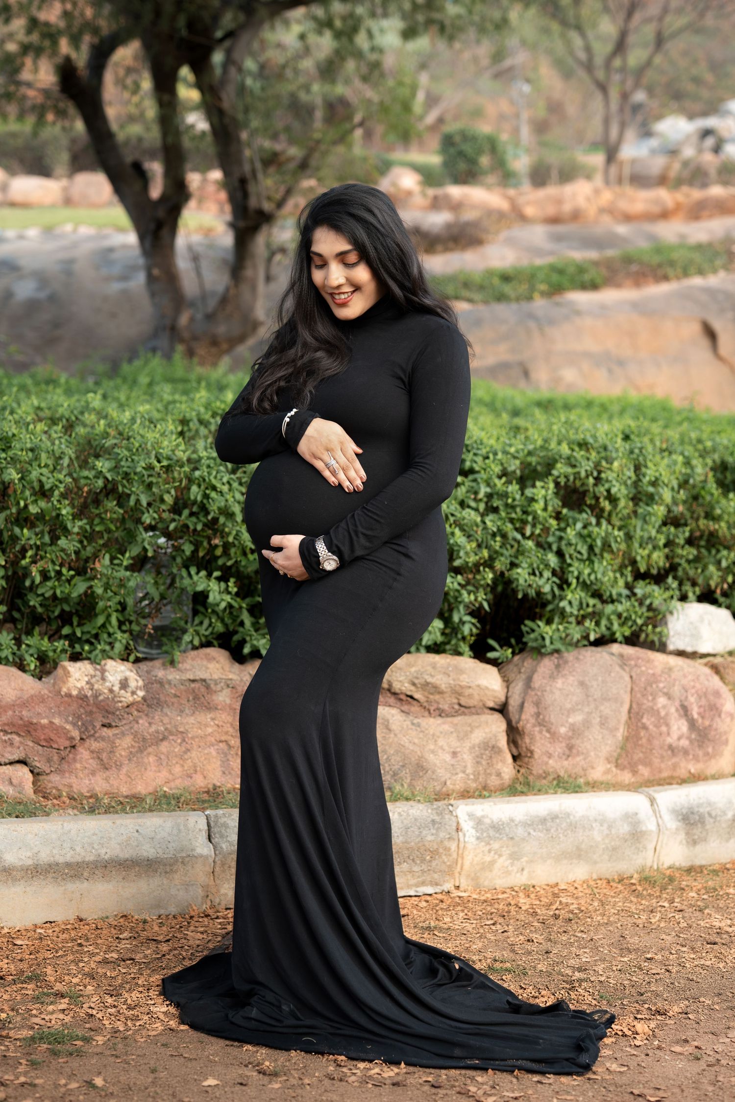 Outdoor maternity photoshoot in Hyderabad with mother in black gown, natural light and greenery capturing calm pregnancy moments
