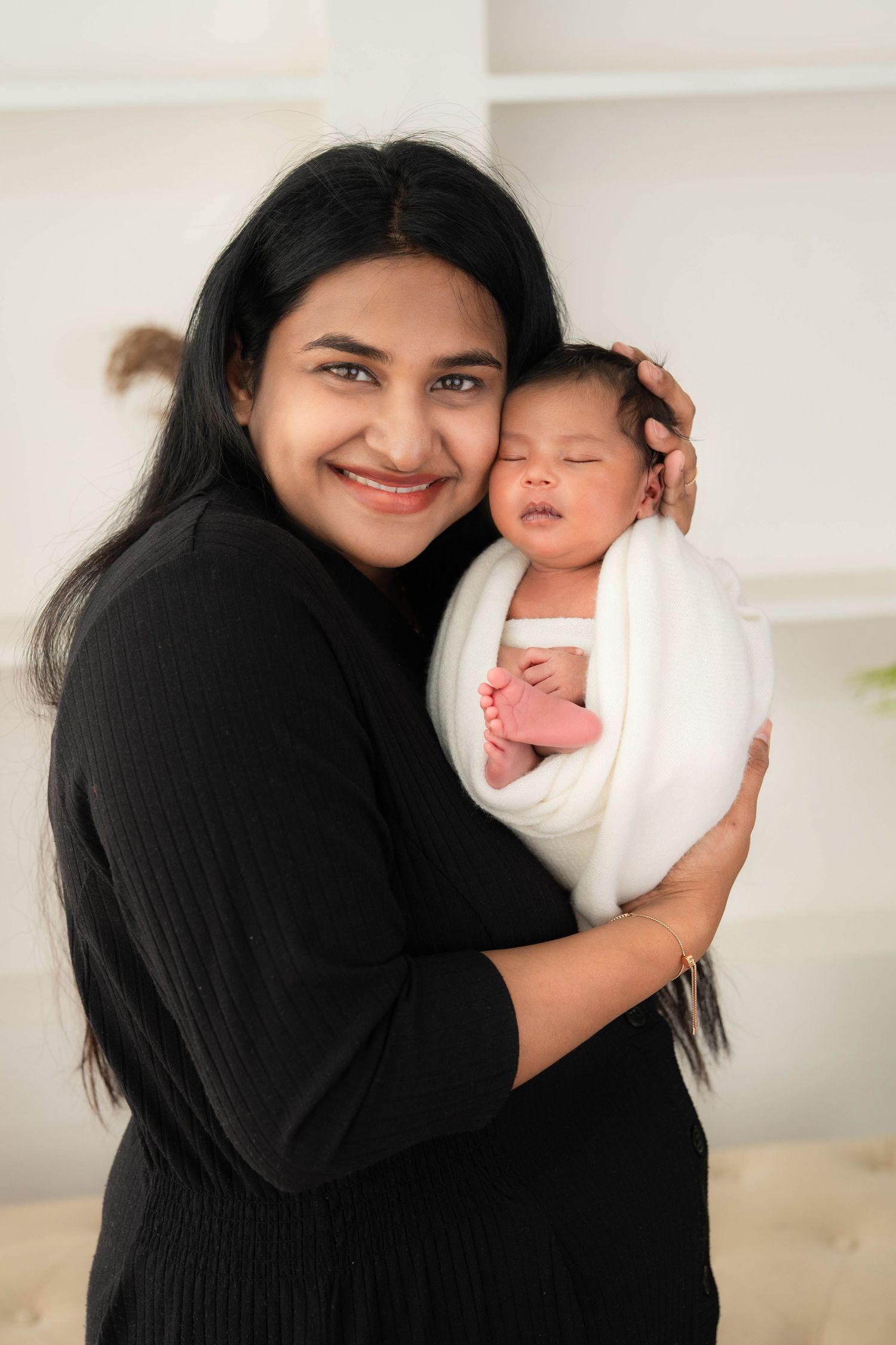 Newborn photography in Hyderabad with mother holding swaddled baby, capturing calm bonding and early motherhood moments
