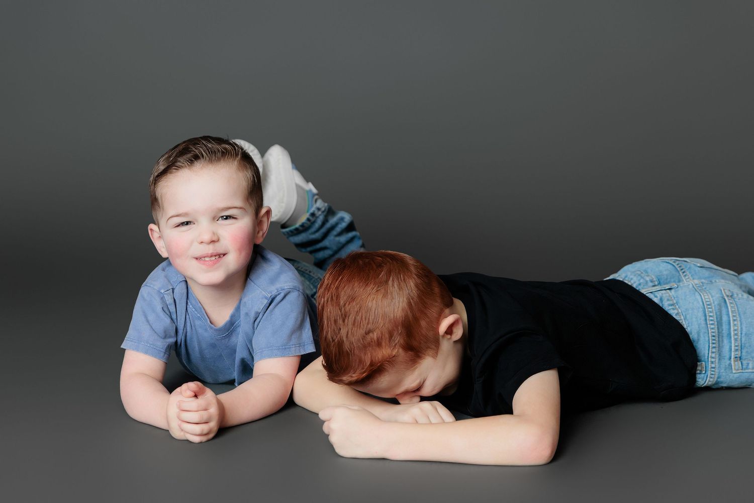 A sequence of black and white studio portraits showing someone laying on their stomach with their head resting on their arms.