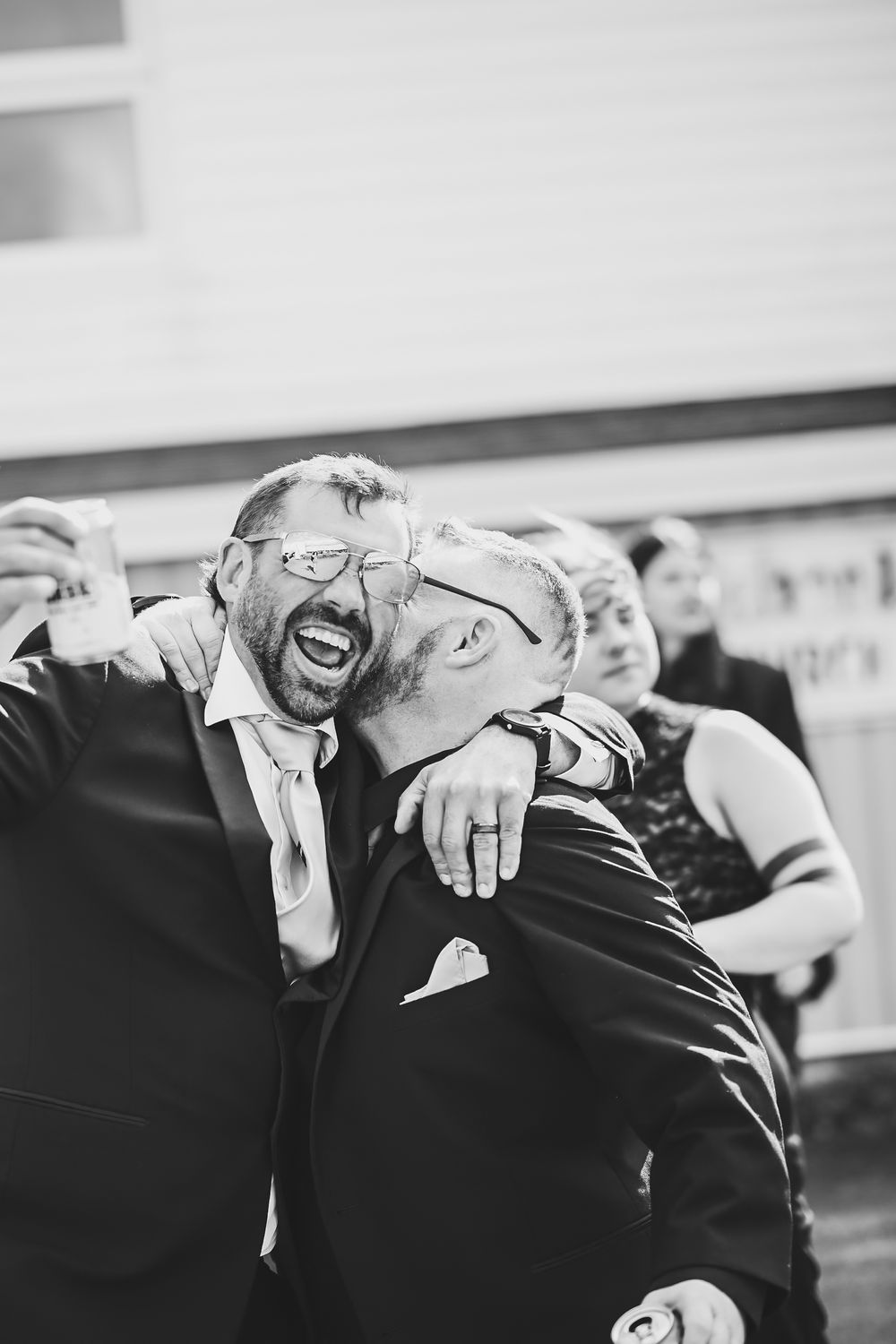 black and white photo of groom kissing groomsman on the cheek, laughing wedding party moment Newfoundland