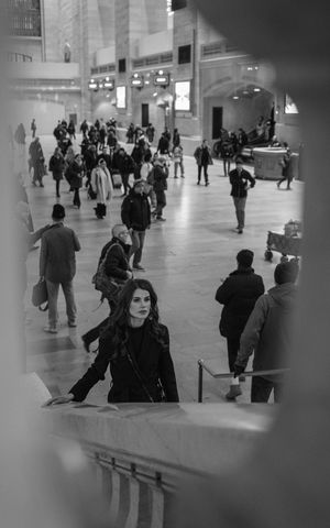 Black and white photo of woman in Grand Central Terminal NYC amid busy commuters.