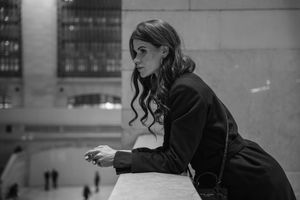 Black and white portrait of woman leaning on railing at Grand Central Terminal NYC.