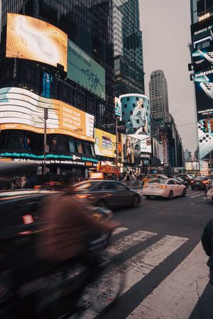 Motion-blurred motorcycle in Times Square NYC surrounded by colorful digital billboards.