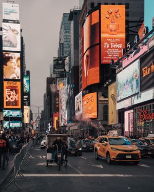 Busy Times Square NYC street with yellow taxis, bright billboards, and city crowds.