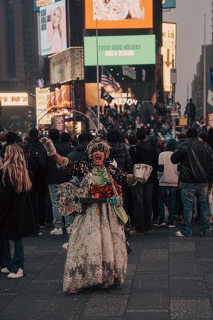 Colorful street performer in elaborate costume at Times Square, NYC, holding cash.