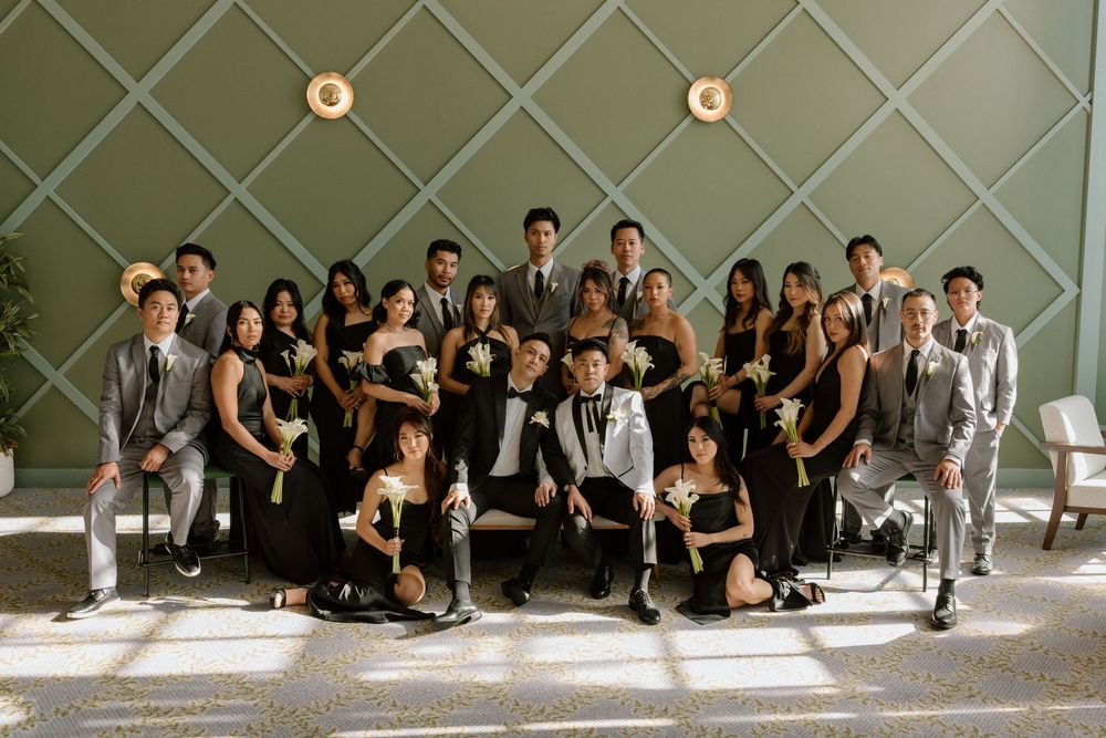 Group of people in formal black and white attire posing together in a modern interior space with geometric walls.