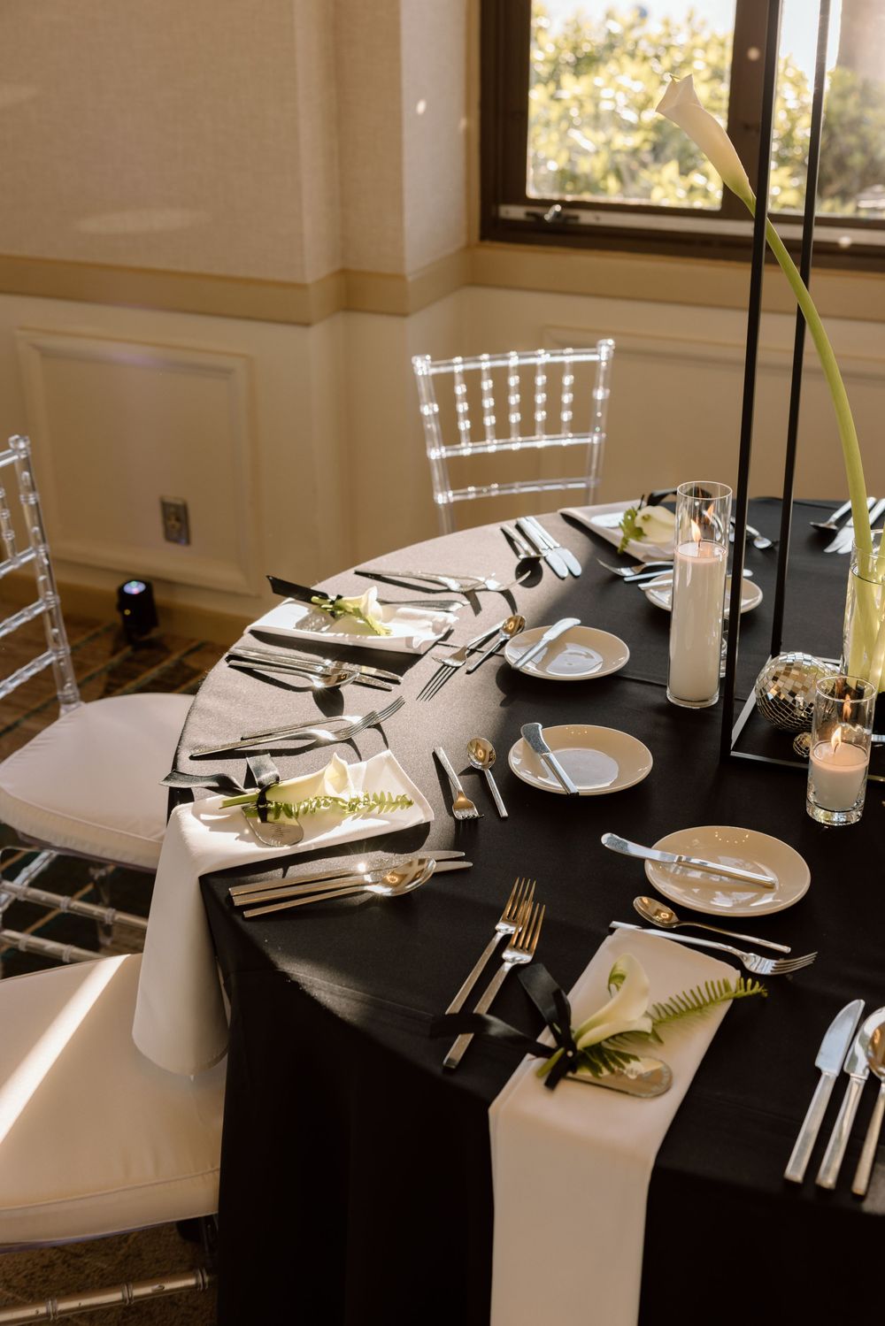 Elegant table settings with black tablecloths, white chairs, and candlelight create a sophisticated dining atmosphere.
