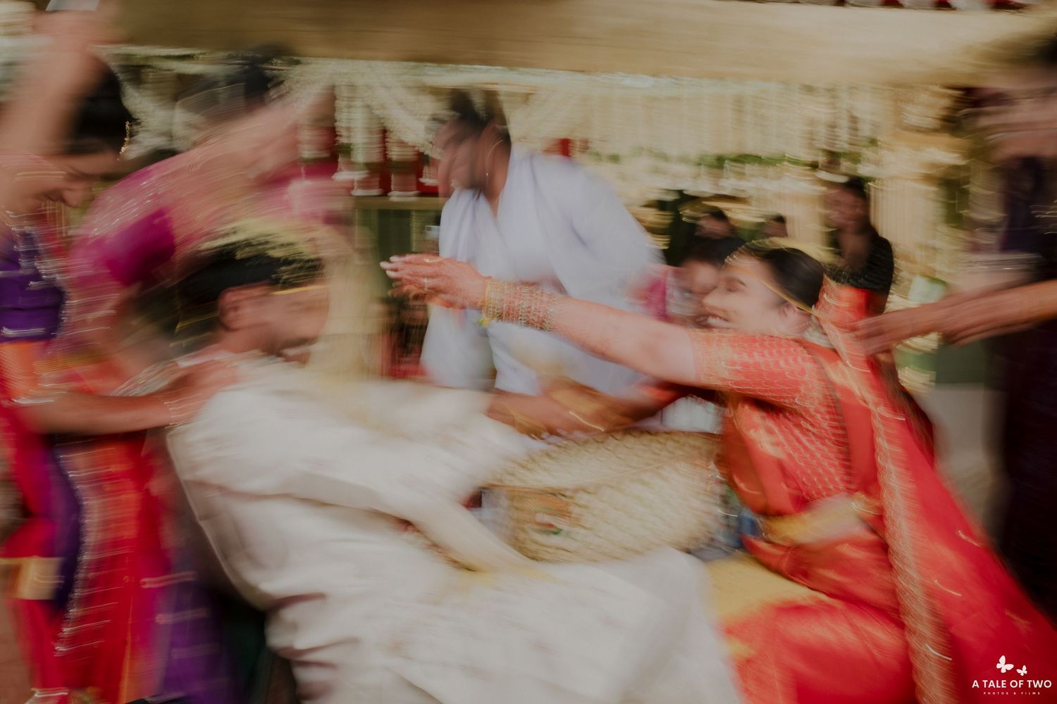 Motion-blurred photo of a joyful dance celebration at a wedding reception with vibrant pink and red colors.