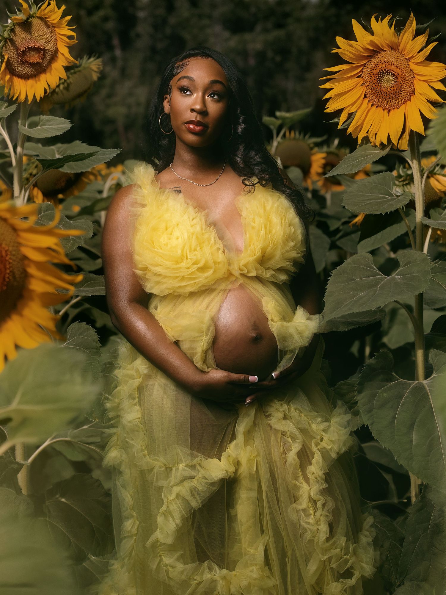 A dreamy portrait in a sunflower field features a flowing yellow tulle gown against vibrant golden blooms and dark foliage.