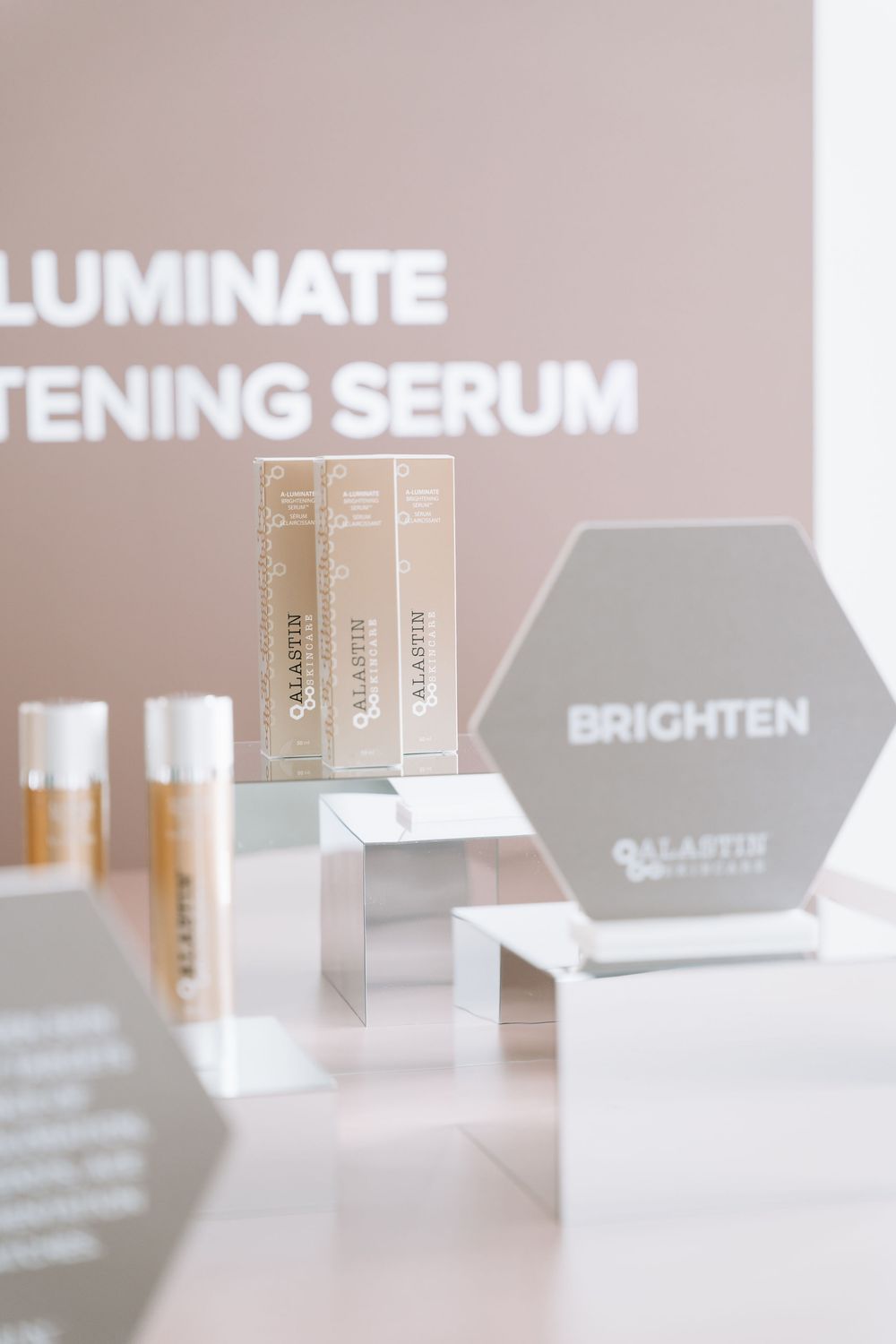 Close-up of beauty product display featuring brightening serum bottles and text on beige background.