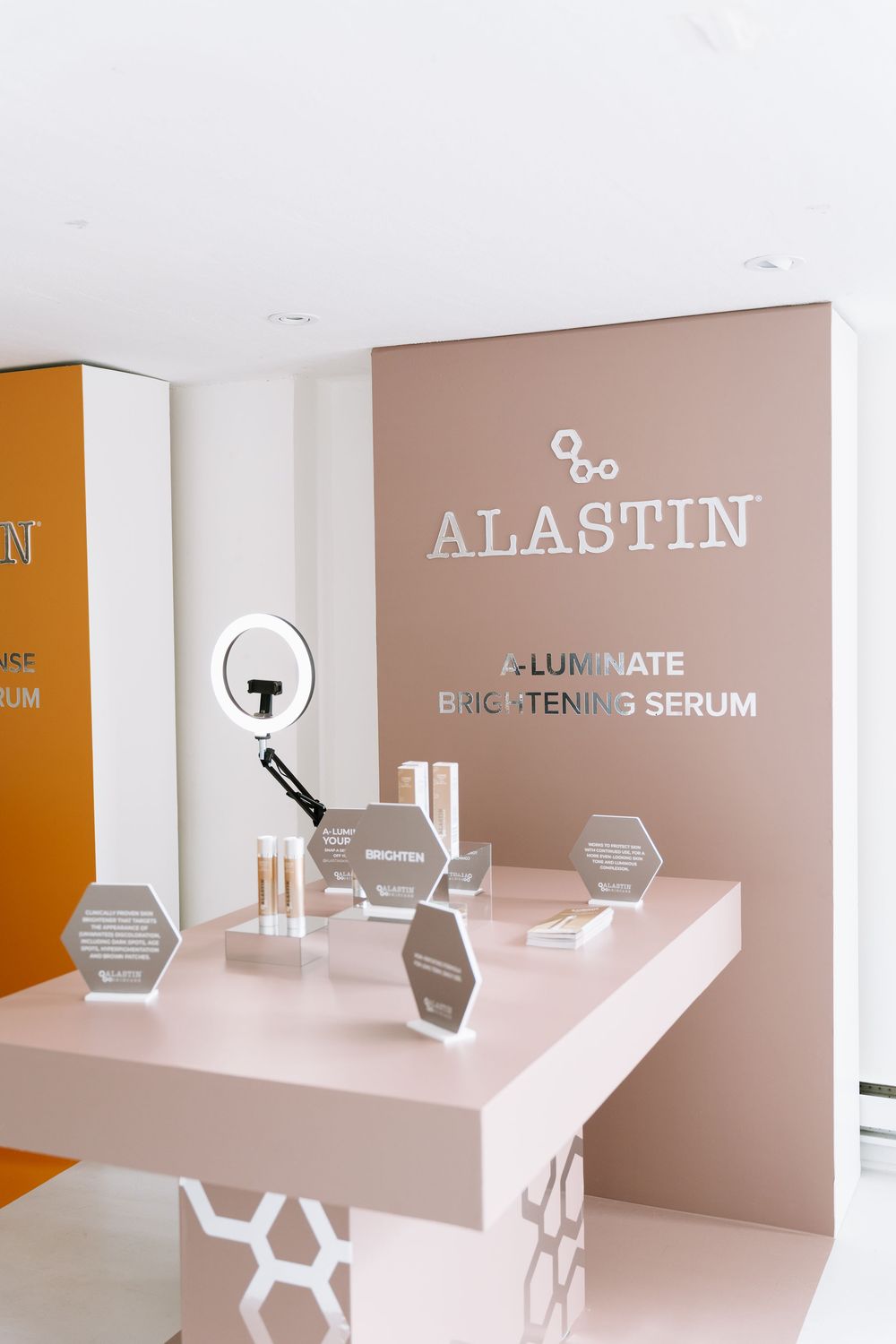 Modern cosmetic display featuring Alastin skincare products on minimalist beige platforms with geometric design elements.