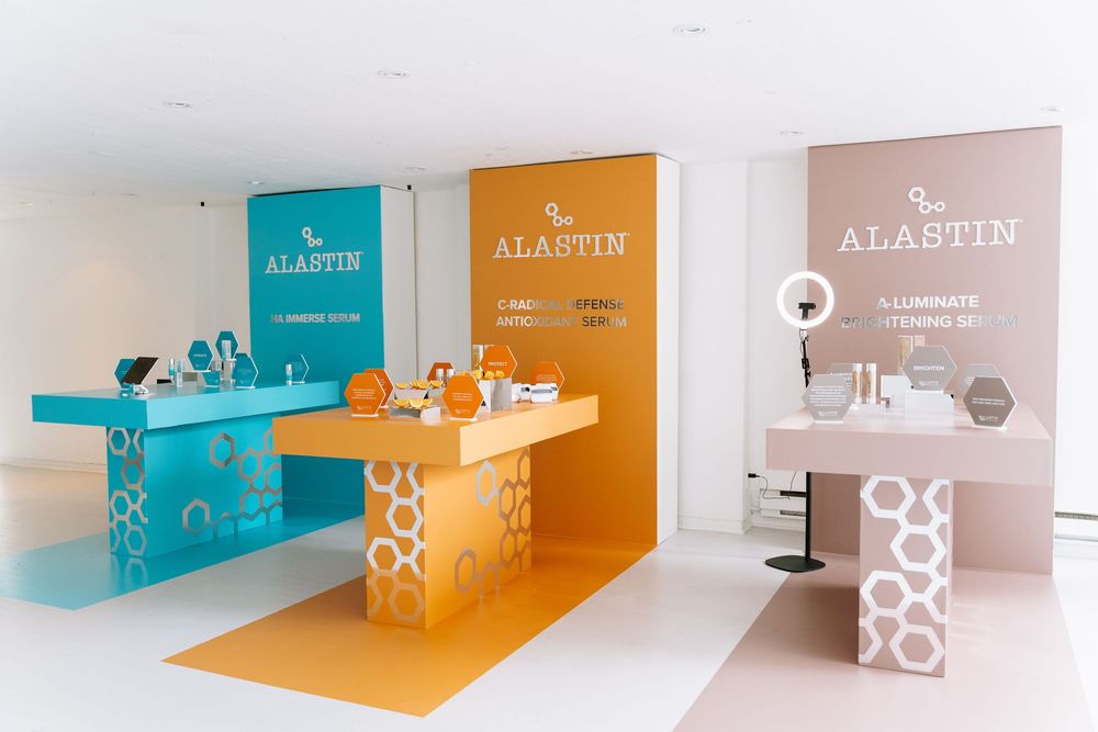 A series of modern retail displays with orange, teal and gray color blocks showcasing Alastin skincare products.