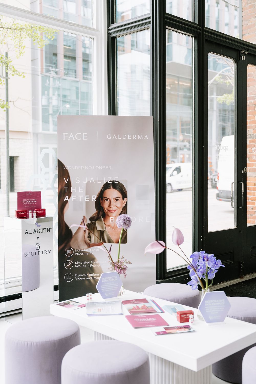 Modern spa interior with white decor, purple accents and promotional materials displayed in window-lined space.