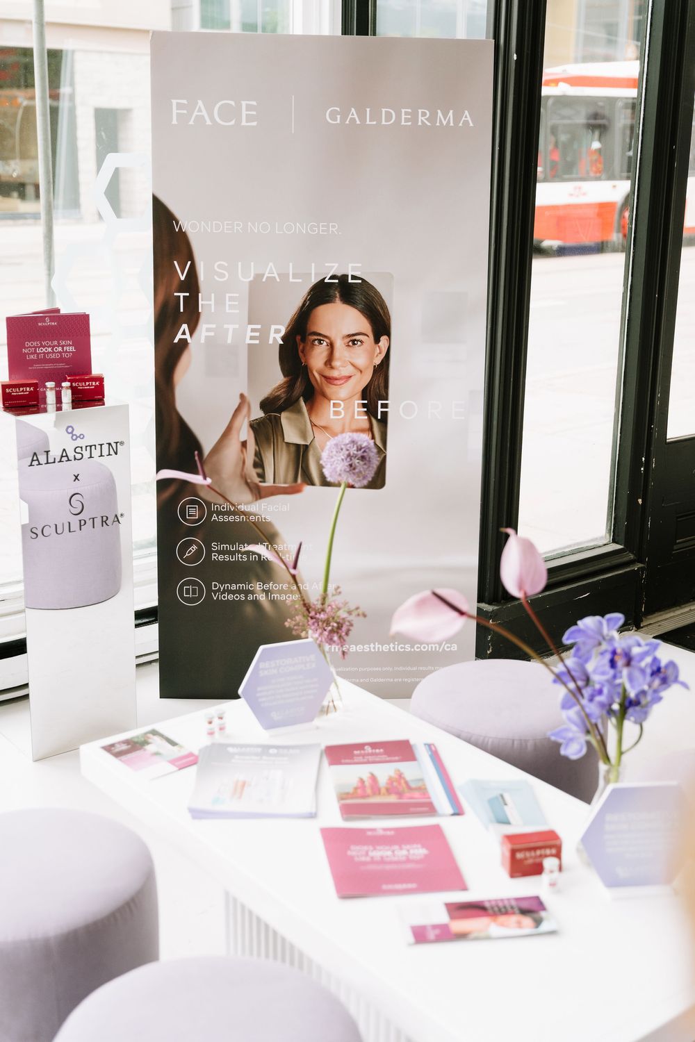 White desk with beauty products, marketing displays and purple flowers in modern spa or salon setting.