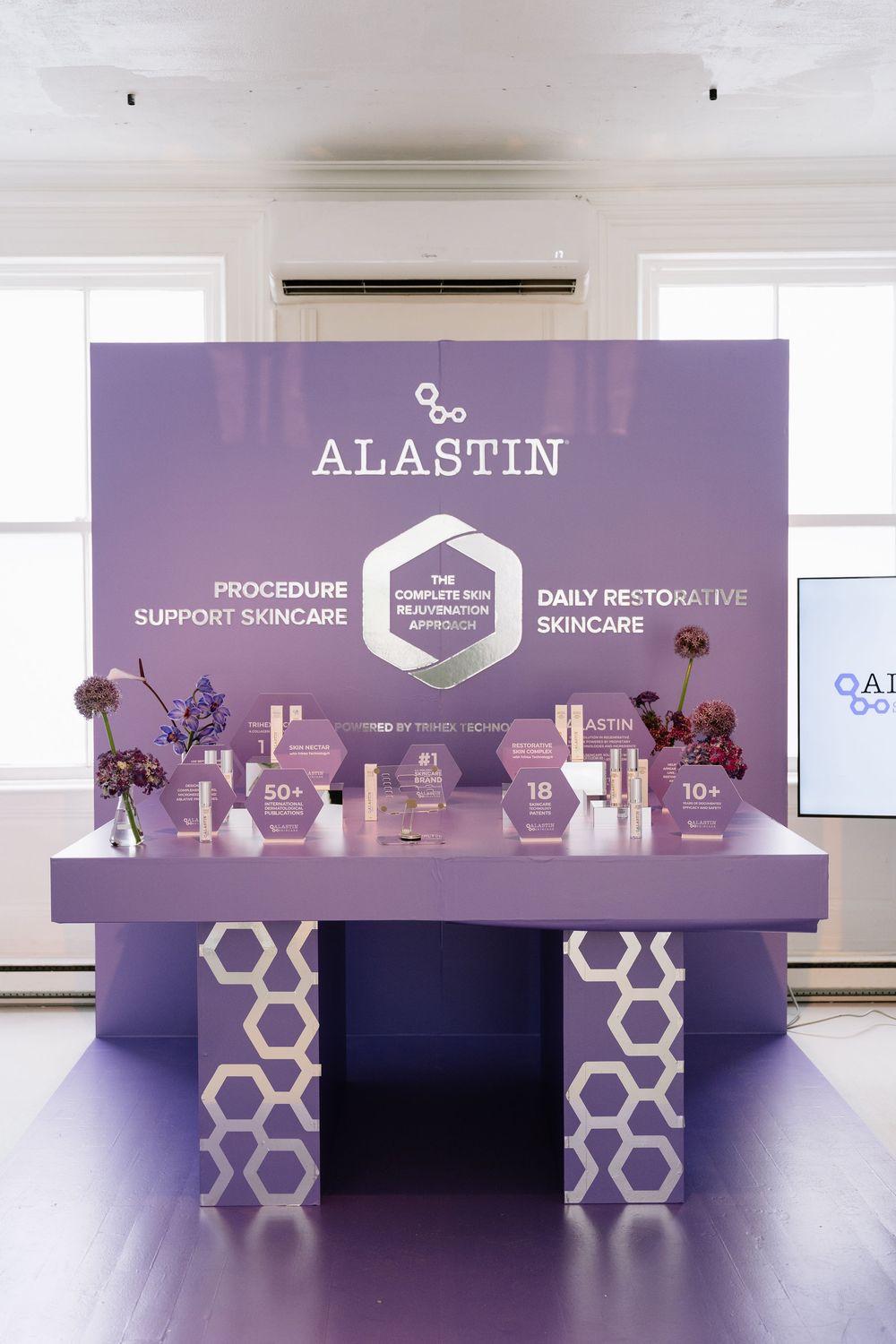 Modern purple and white exhibition display setup with geometric branding elements and company logo.