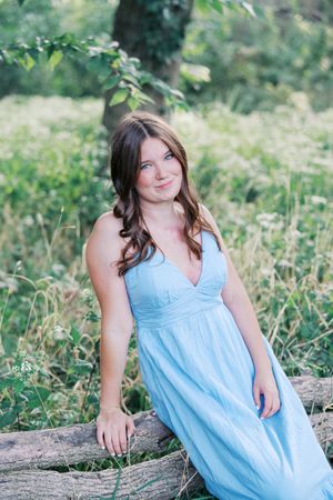 Outdoor portrait session in light blue dress against natural greenery background.