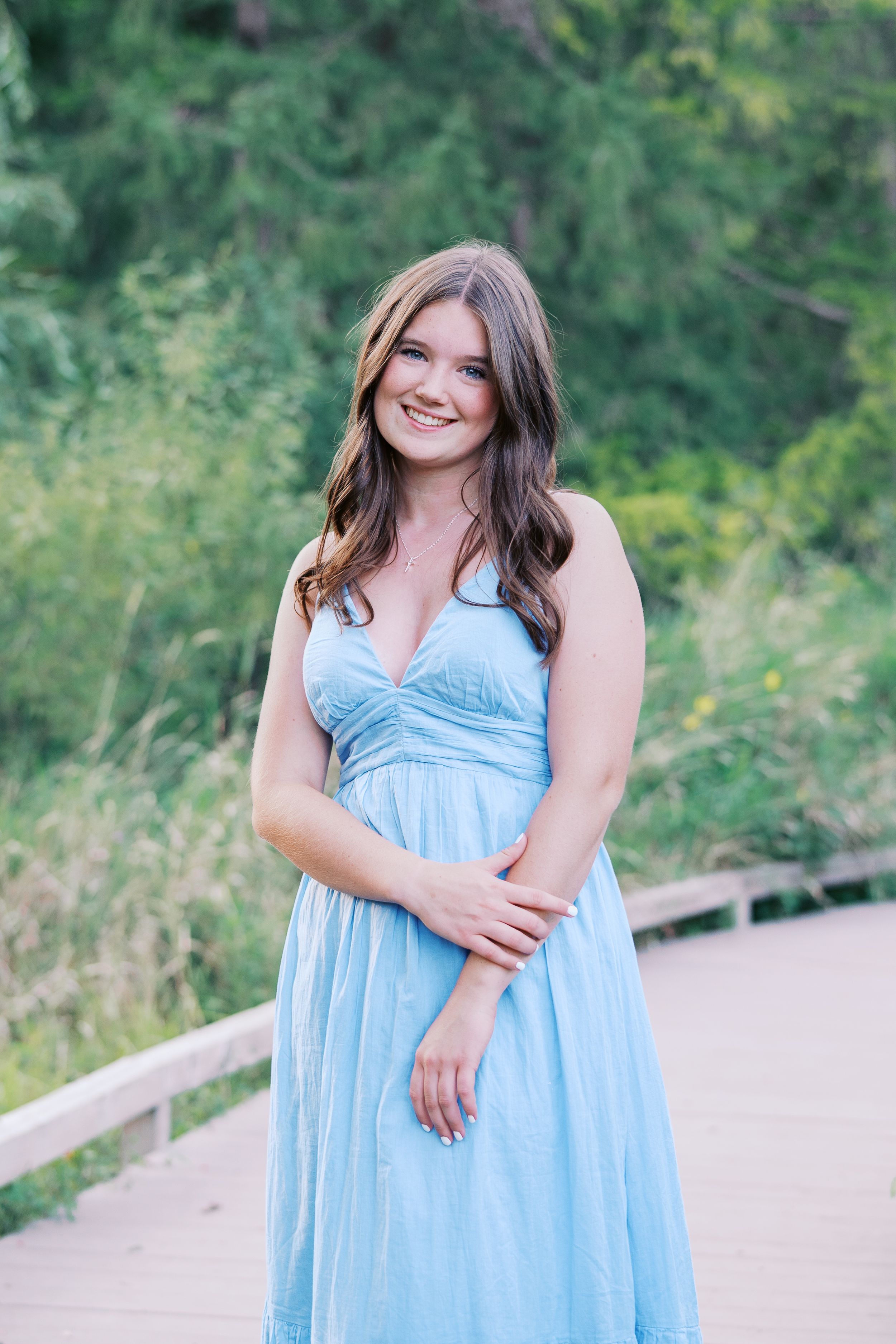 Summer portraits in flowing light blue dress on nature path.