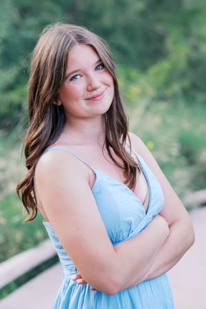 Candid expressions in light blue dress against natural backdrop.