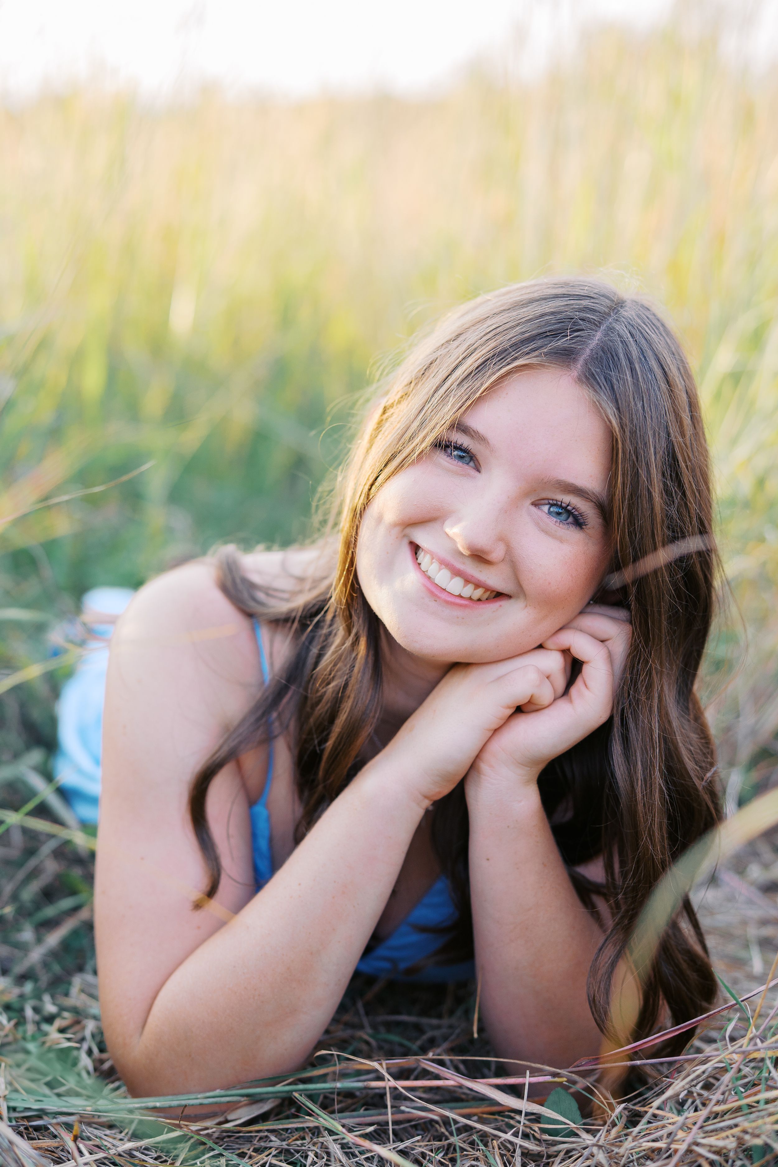 Candid portraits lying in golden grass during a summer photoshoot.