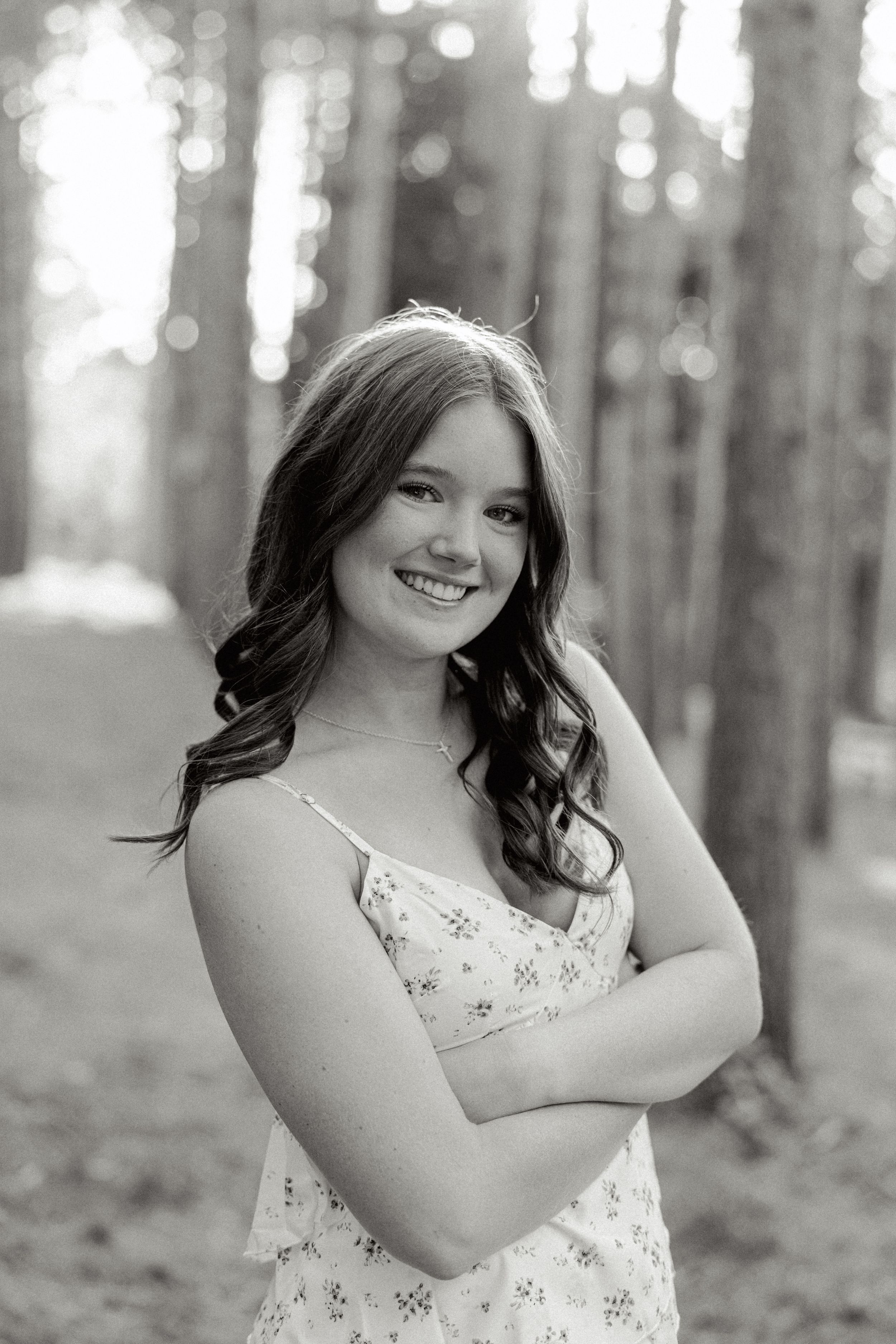 Black and white portrait in a pine forest with soft bokeh lighting effects.