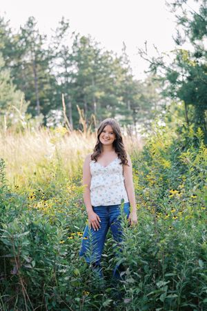 Summer portrait in a wildflower meadow wearing a floral camisole and jeans.