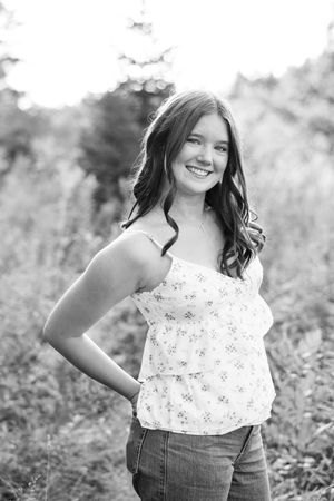 Black and white portrait in a natural setting with joyful expression.