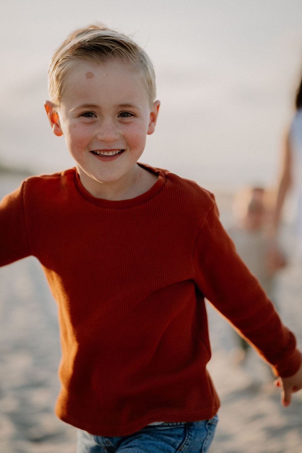 Series of candid shots showing playful moments in a red sweater on the beach at dusk.