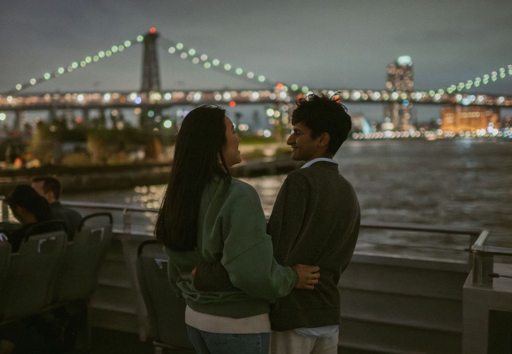A couple enjoys a romantic evening view of the illuminated Williamsburg Bridge in New York City.