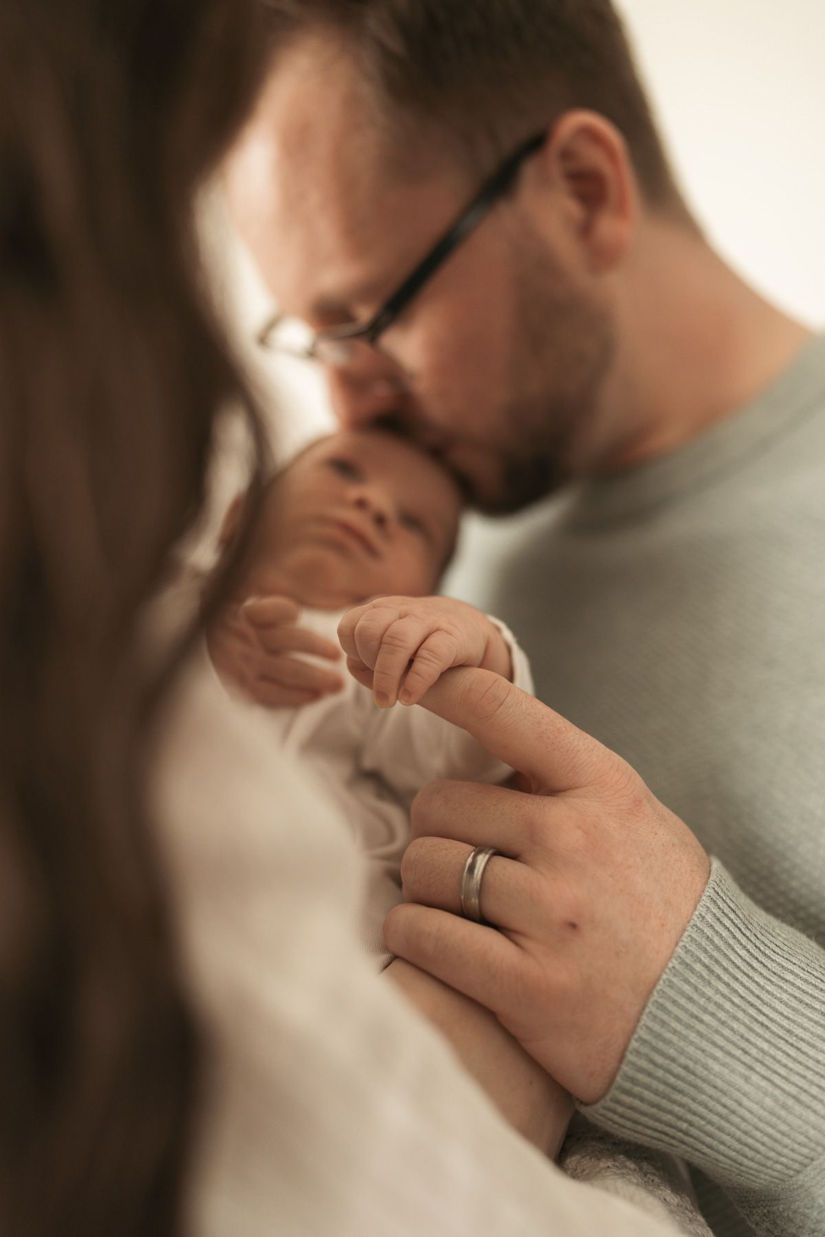 Close-up view of hands with wedding rings in soft natural lighting showing an intimate romantic moment.
