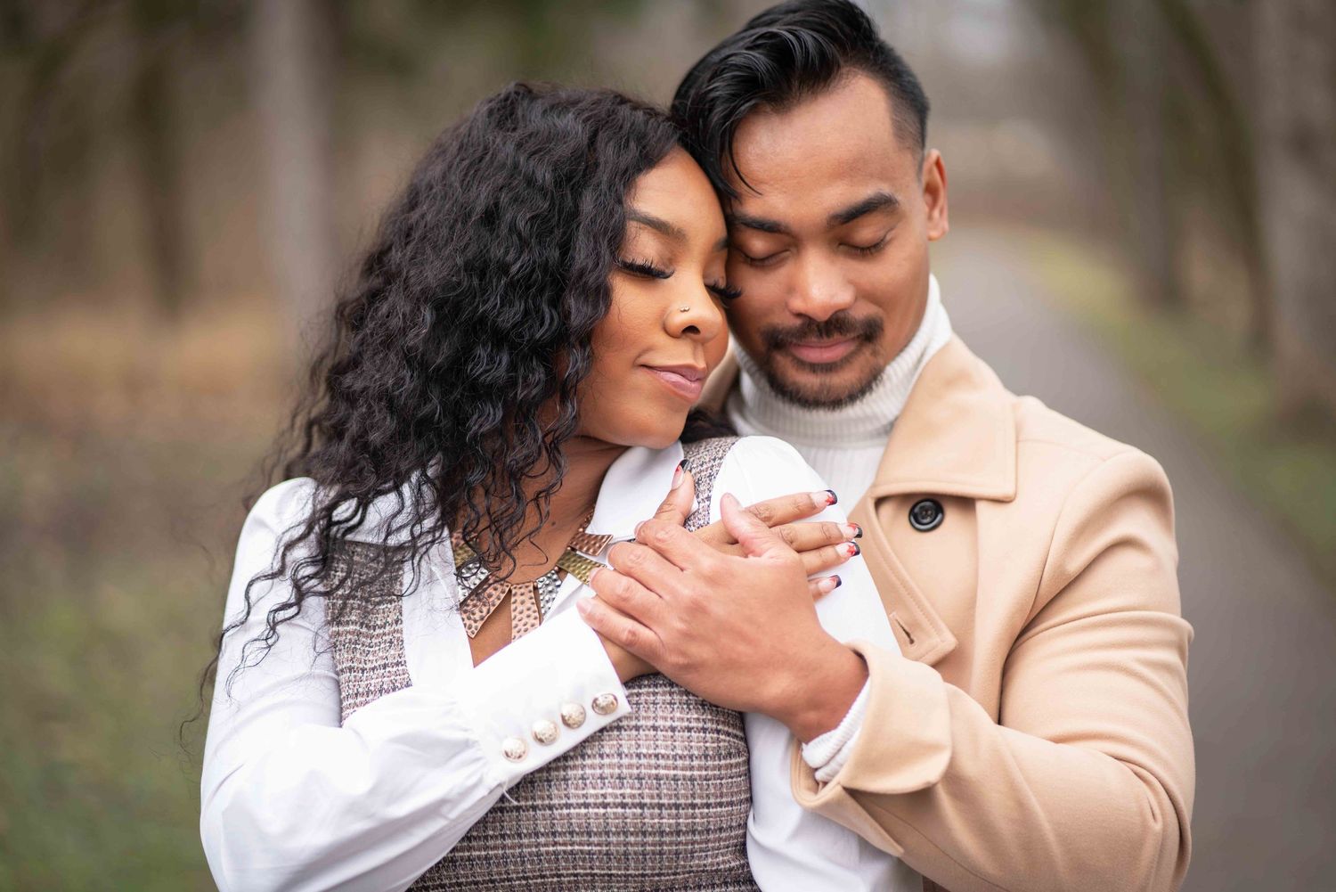 A couple embraces tenderly in a romantic outdoor photoshoot wearing coordinated beige and white outfits.