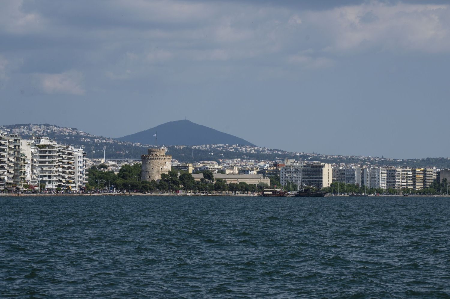 Panoramic coastal cityscape view with mountains in the background and blue Mediterranean waters in the foreground.
