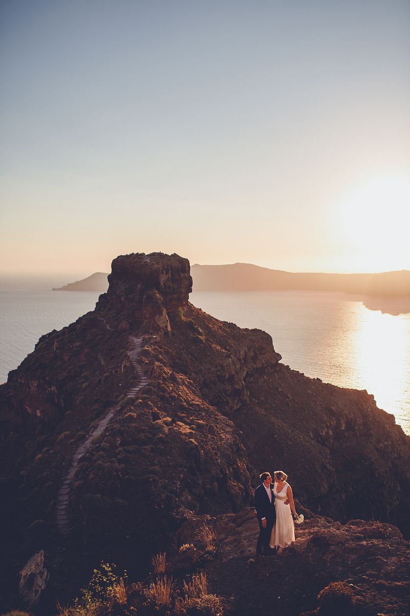 Couple on volcanic cliffs at sunset in Santorini overlooking the caldera