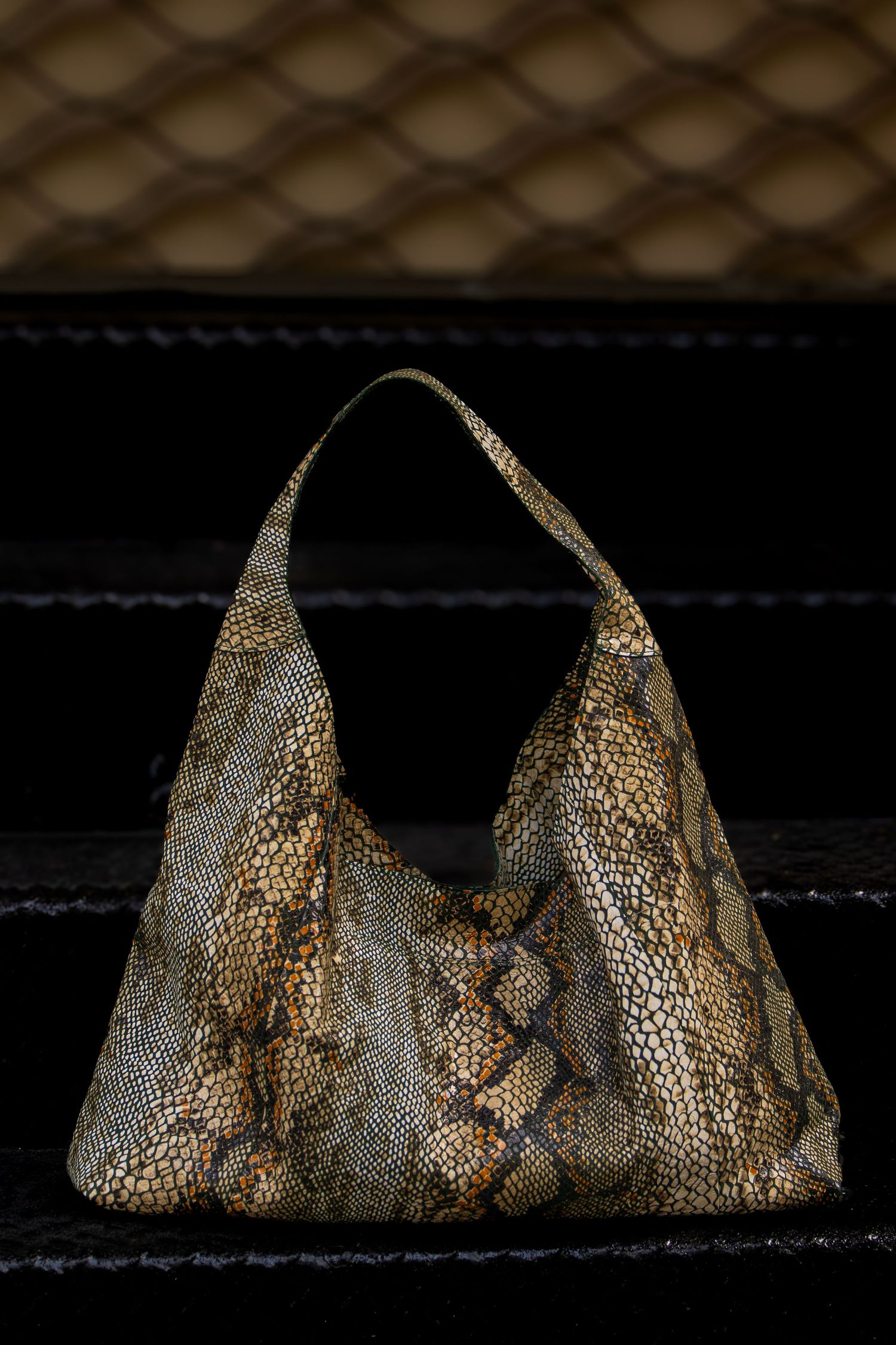 Luxurious snakeskin pattern hobo shoulder bag in tan and brown tones displayed on dark velvet surface.