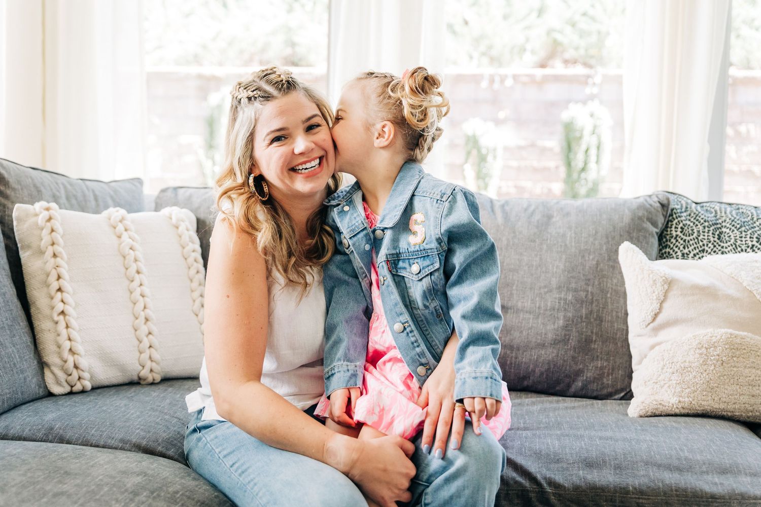 Two people share a joyful moment while sitting together on a gray couch with decorative pillows in Charlotte, NC.