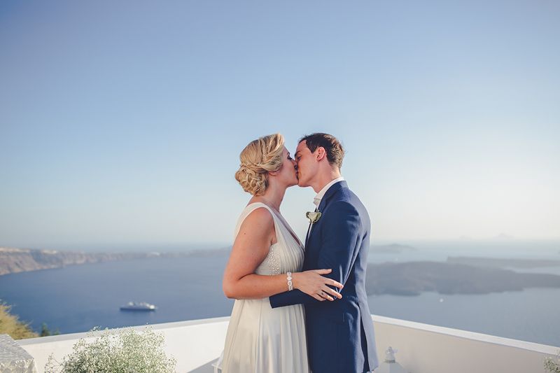 Bride and groom kissing overlooking the caldera in Santorini