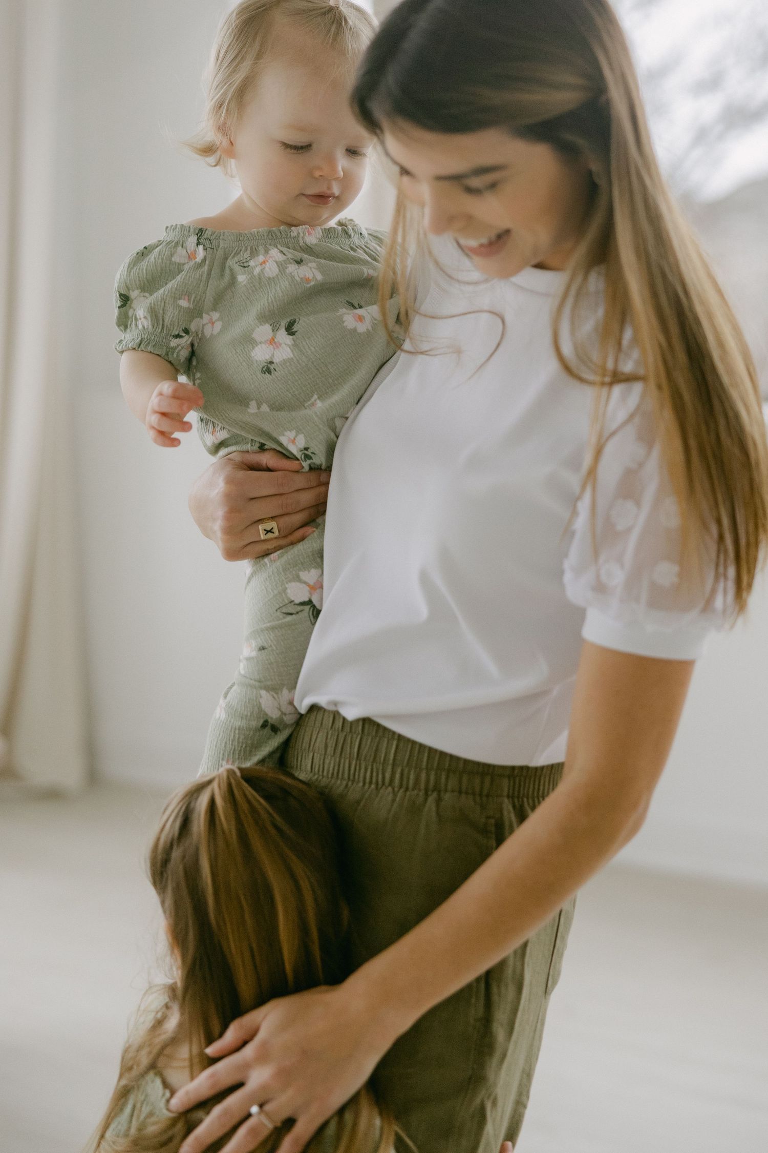 A tender moment between parent and child wearing coordinating olive green outfits against a bright white backdrop.