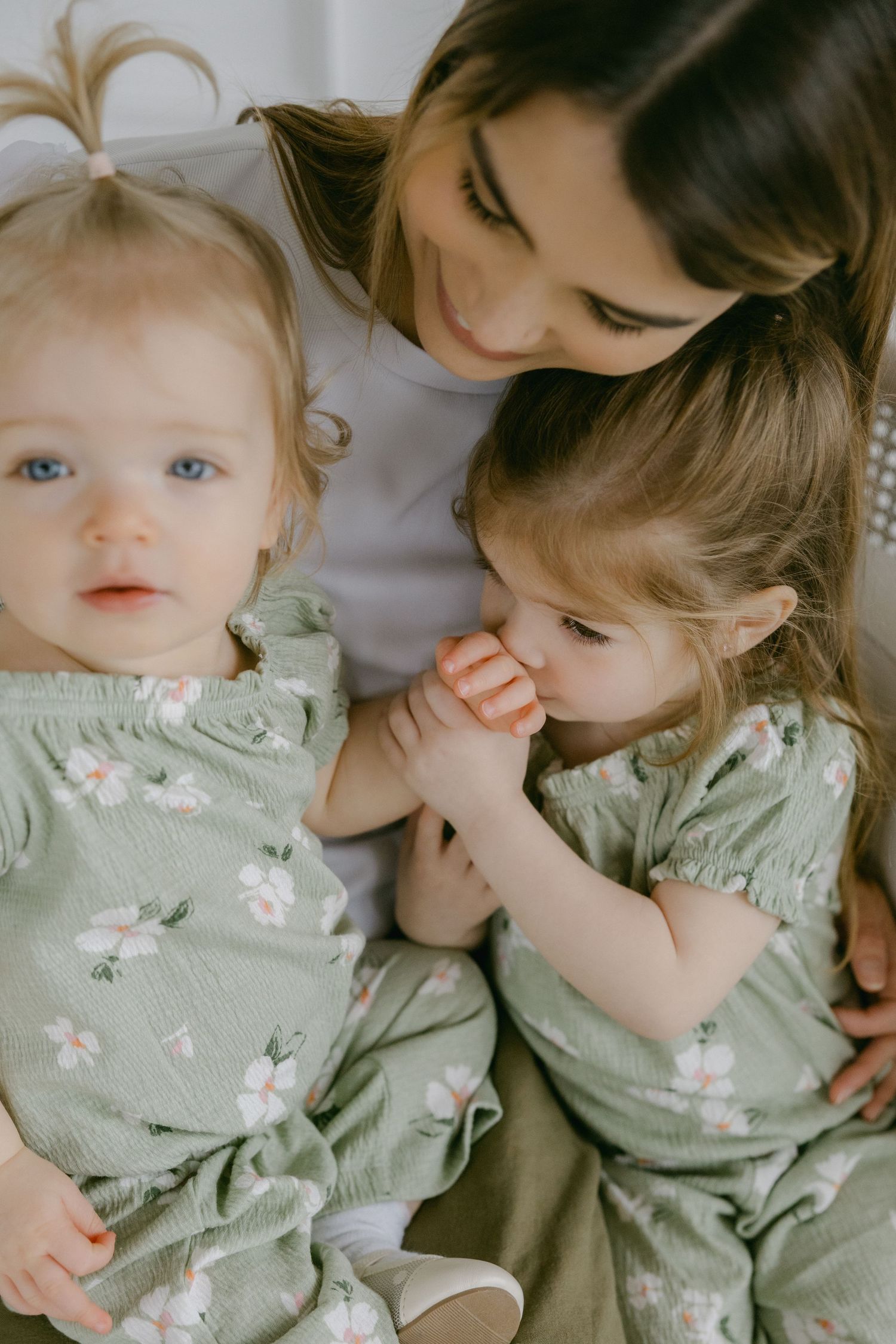 A series of tender moments captured in soft lighting showing a baby in a mint green floral dress with a caregiver.
