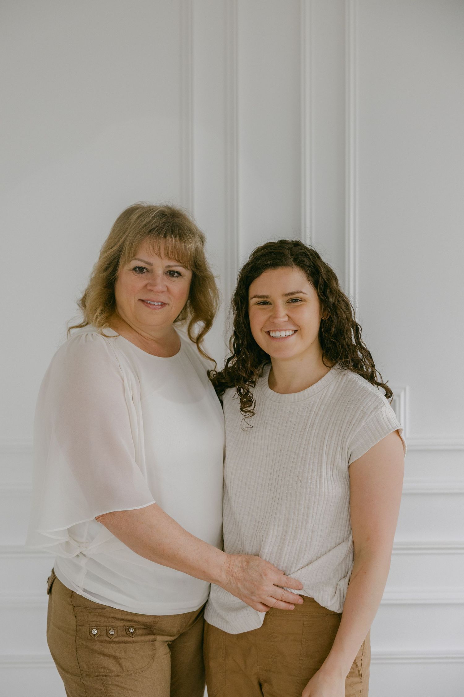 Two people in casual attire pose together against a white wall in a series of candid shots.