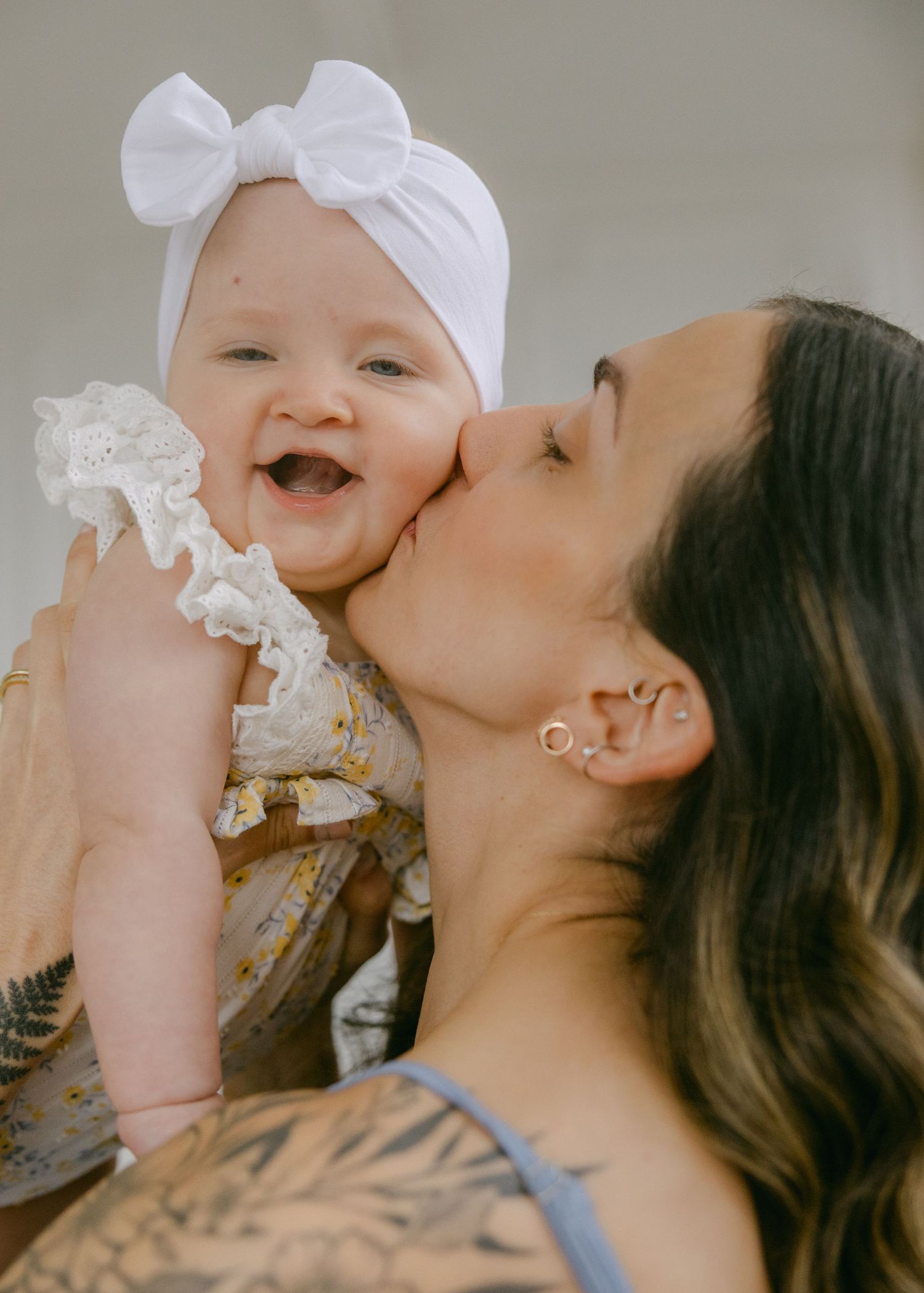 A tender moment between parent and baby in white bow headband shown in multiple sweet kisses and interactions.