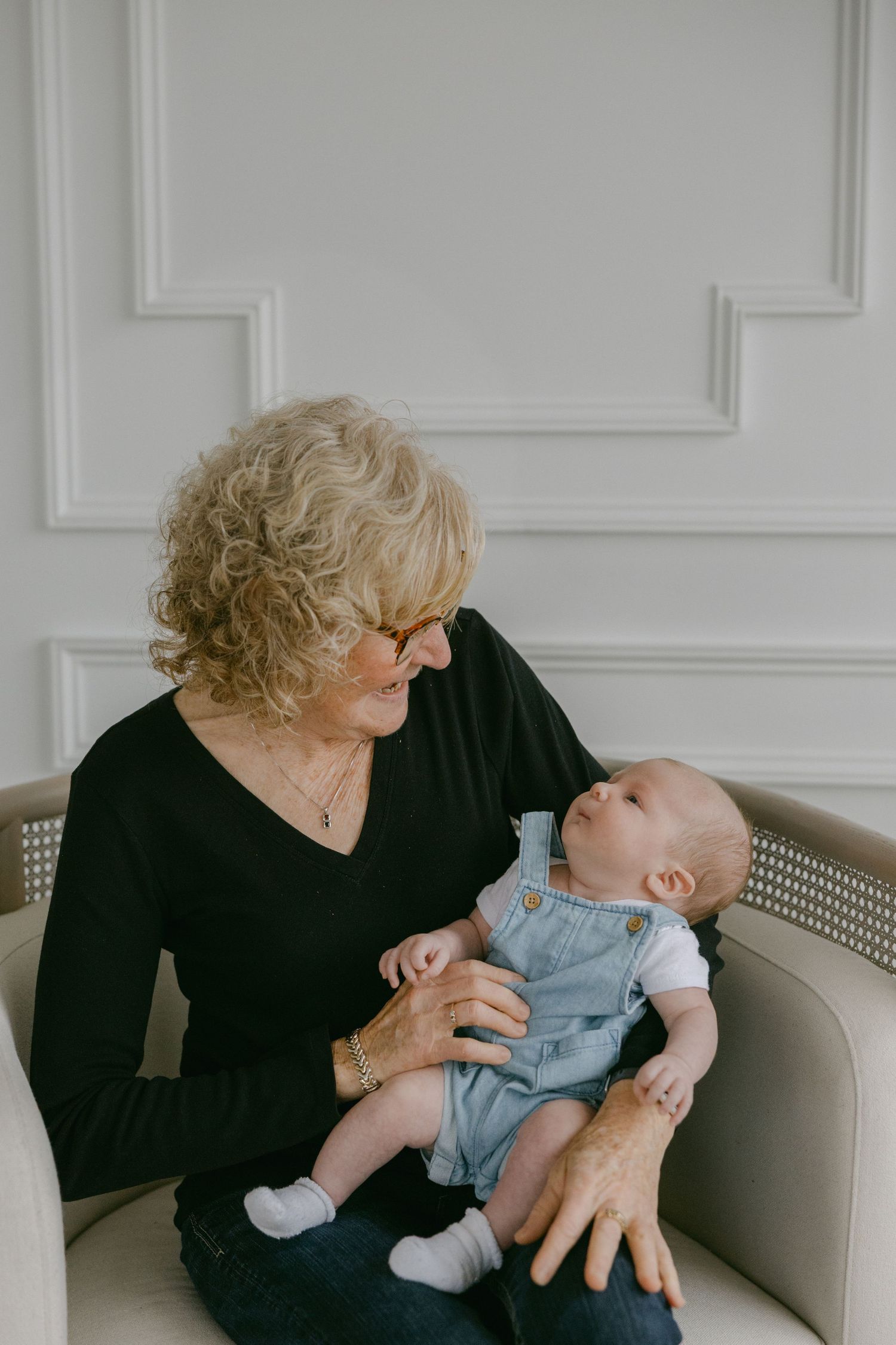 A series of three candid photos showing tender moments between a person in black and a baby on a light colored couch.