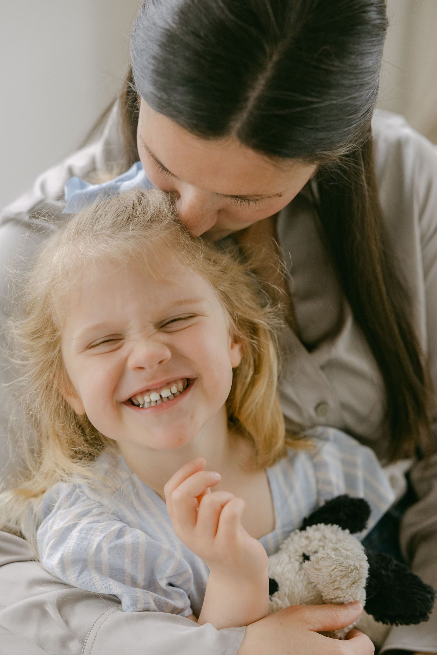 A tender moment shows a parent and child sharing laughter and cuddles while lying down together.