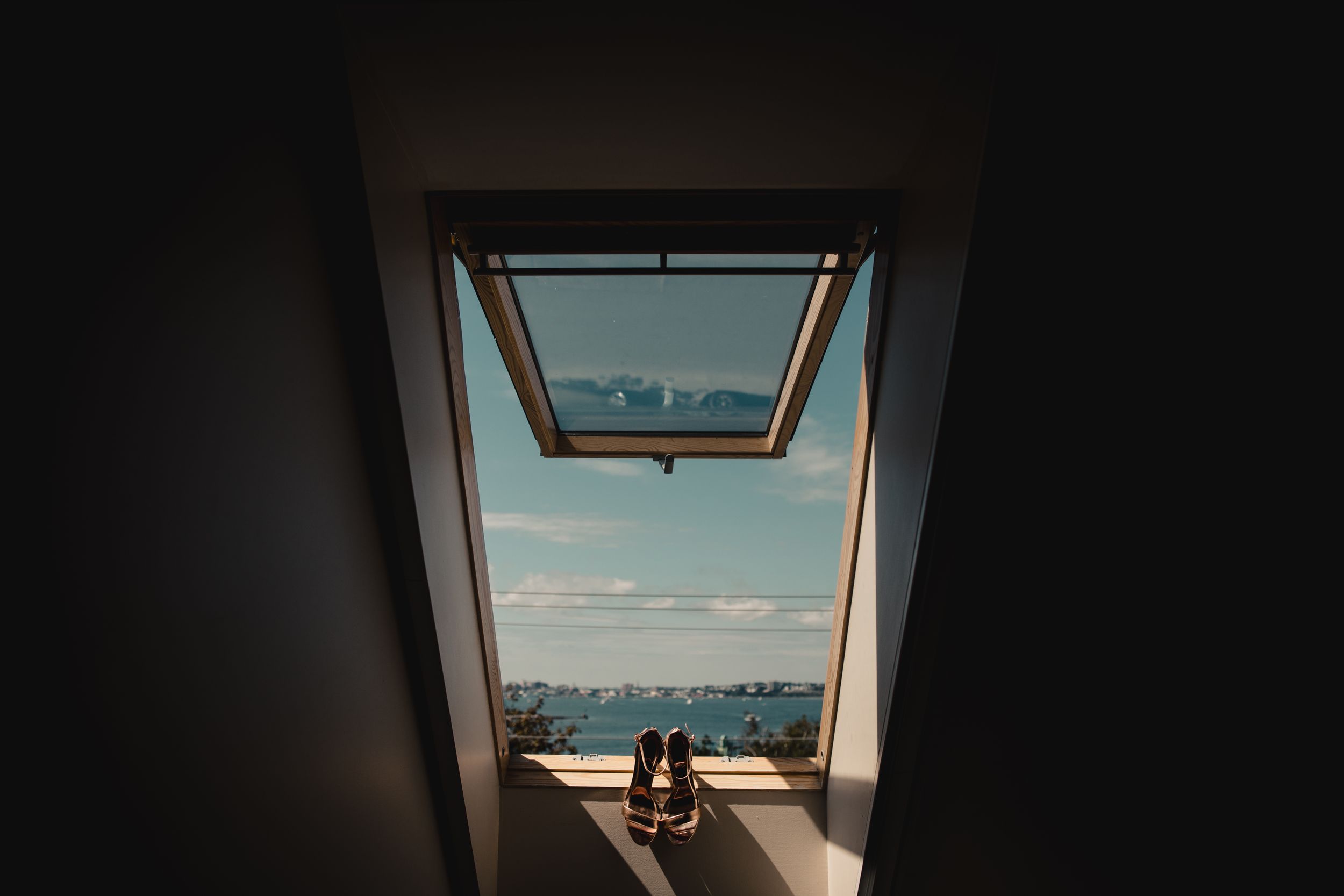 Shoes silhouetted in a skylight window with a scenic lake and mountain view on a sunny day.