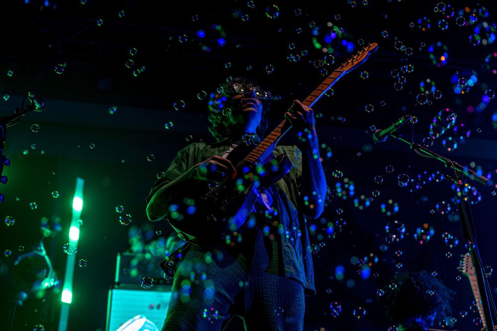 Colorful lights and bubbles create a magical nighttime atmosphere at an outdoor event.
