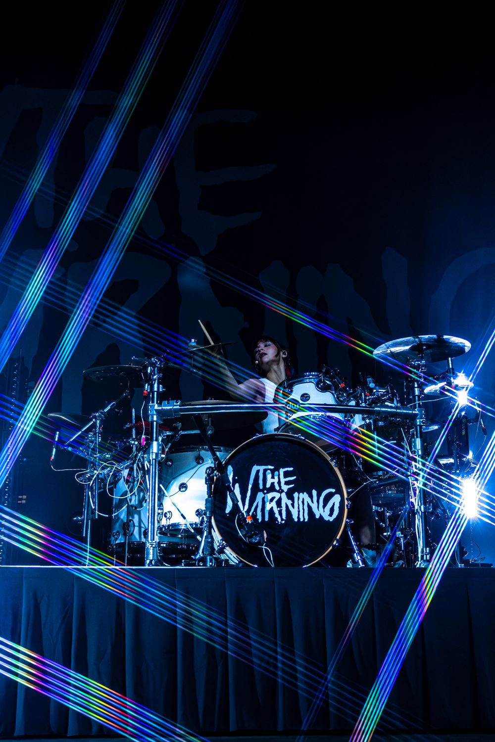 Concert stage illuminated with dramatic blue laser lights and fog effects creating an atmospheric performance environment.