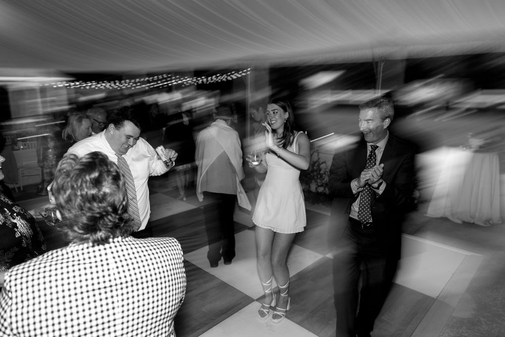 Black and white photo series showing guests dancing and celebrating at a lively wedding reception.