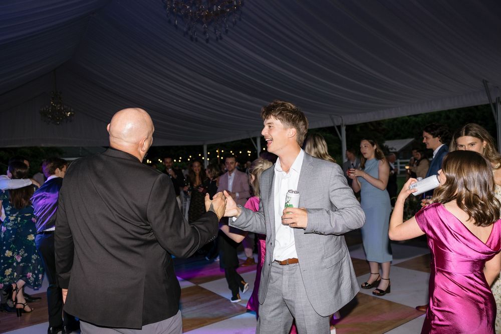 People dancing and socializing at a dimly lit indoor party venue with white tent-like ceiling decor.