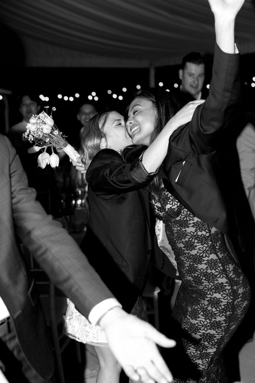 People dancing and having fun at a dimly lit party with string lights visible in the background.